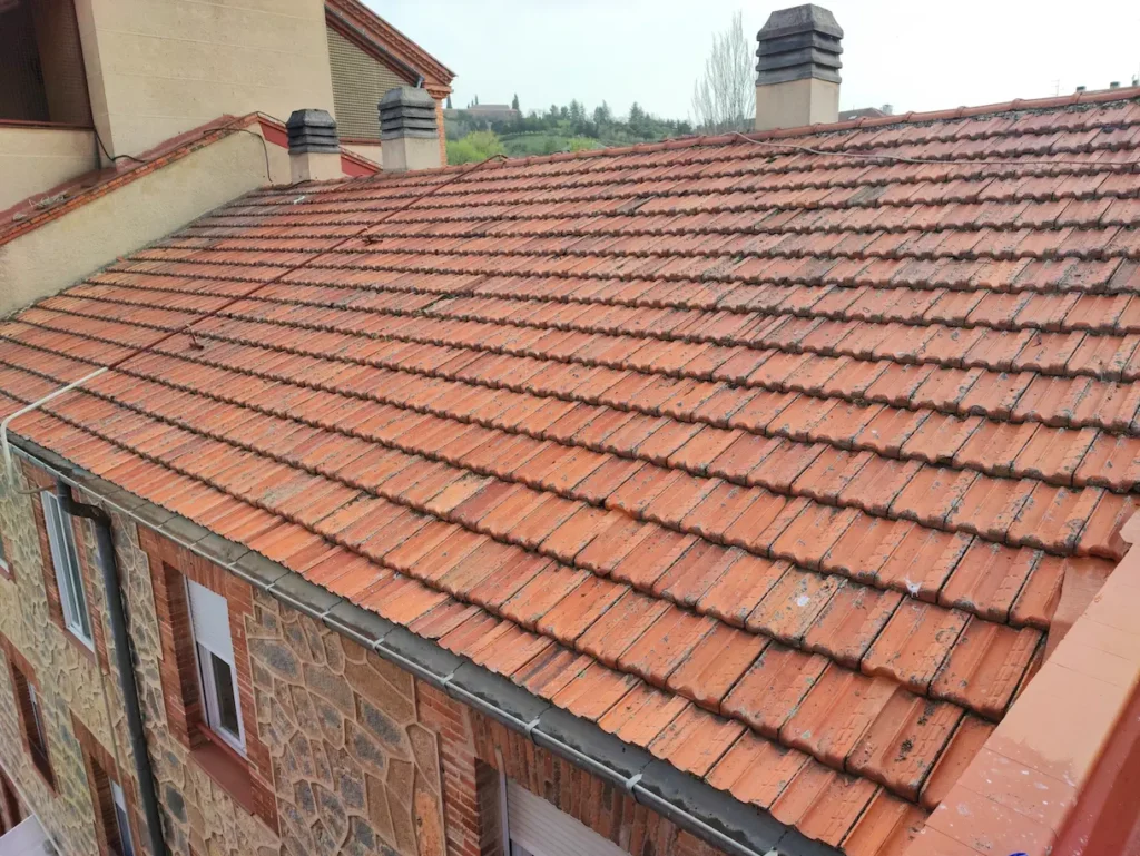 Tejado completamente limpio y en perfecto estado tras la reparación de filtraciones, mostrando las tejas restauradas y canalones despejados en una vivienda de Segovia.