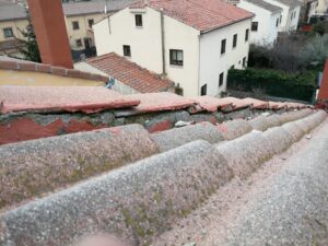 Tejado en Segovia con tejas desplazadas y mortero deteriorado, mostrando grietas y levantamientos causados por el viento y el paso del tiempo. Imagen real tomada durante una revisión de Tejados Segovianos.