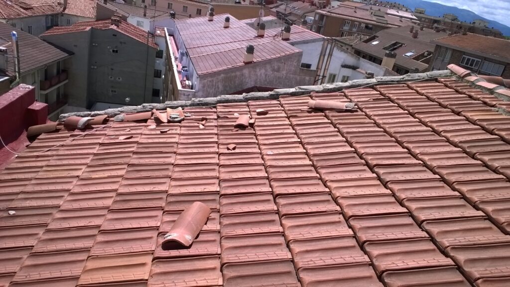 Tejas voladas sobre el tejado, que han estado a punto de caerse debido al aire.